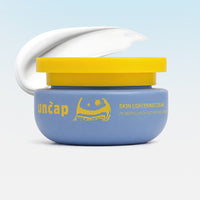 Blue jar of Uncap skin lightening cream with yellow lid on a light blue background